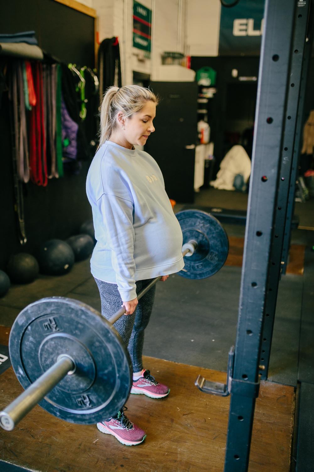 pregnant woman lifting a bar weight in a gym